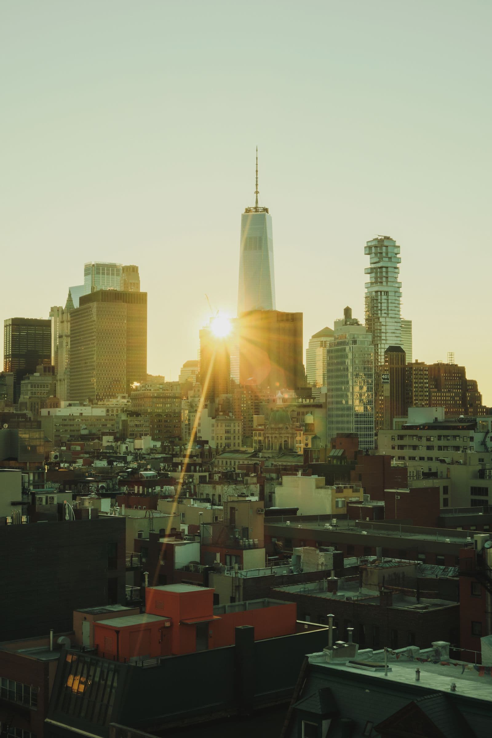 Lower Manhattan's financial district at sunrise, One World Trade Center catching the first light above the skyline