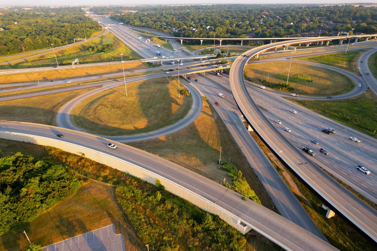 A golden-hour aerial view of a highway interchange — sweeping ramps and merging lanes forming one connected system of flows